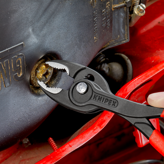 KNIPEX TwinGrip Frontgreifzange beim Greifen einer rostigen Schraube, schwarze Zange mit roten Griffen, Frontgreifmaul mit