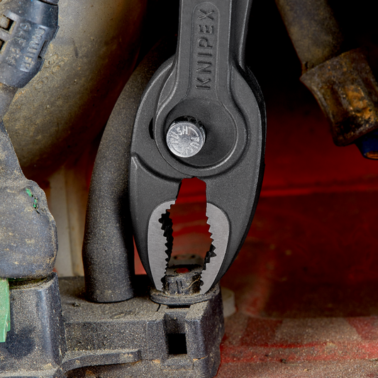 KNIPEX TwinGrip Frontgreifzange mit gezahntem Frontgreifmaul beim Greifen eines roten Werkstücks, Detailansicht der