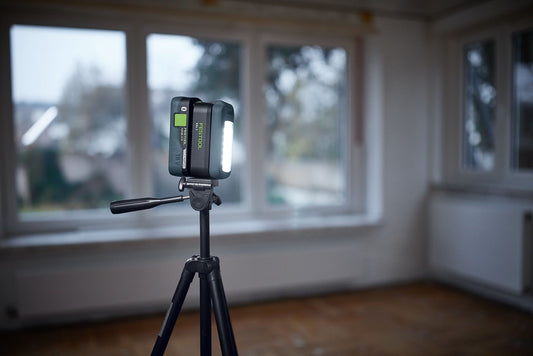 Festool SYSLITE KAL C Akku-Arbeitsleuchte auf Stativ mit leuchtenden LED-Leuchtkopf in Baustelle
