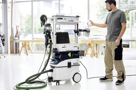 Festool CLEANTEC CTL 36 EI Absaugmobil in Werkstatt, Mann bedient Touch-Display mit Saugschlauch und Werkzeughalterung.