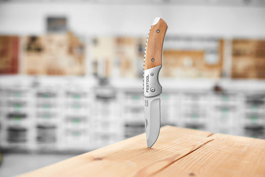 Festool Arbeitsmesser KN-FT1 mit Olivenholz-Griffschale, ausgeklappt auf Holzoberfläche.