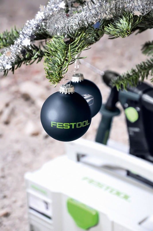 Festool Weihnachtskugeln WK-FT3 dunkelblau mit Logo an Fichtenast mit Reif, Elektrowerkzeug im Hintergrund