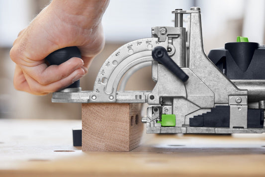 Festool DOMINO DF 500 Dübelfräse mit Anschlagpins beim Fräsen von Dübelposition in Holz, Winkelskala sichtbar.