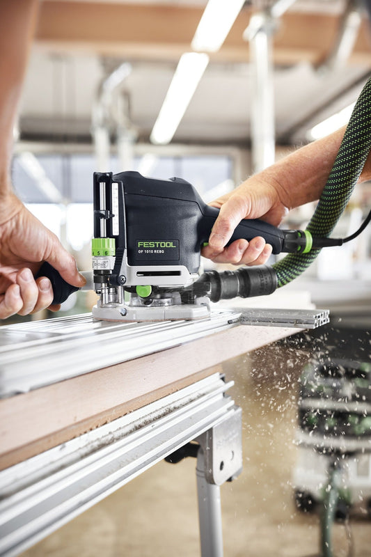 Festool OF 1010 REBQ Oberfräse mit Führungsschiene beim Fräsen von Nut in Holzwerkstück, Späne fliegend