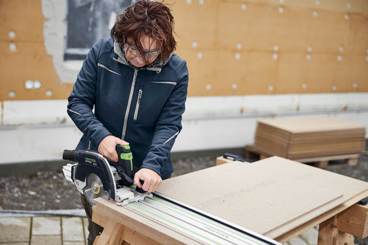 Frau nutzt Festool Handkreissäge mit Führungsschiene zum Sägen von Holzwerkstoff auf Baustelle