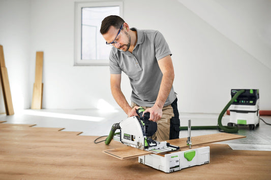 Festool Tauchsäge TS 60 KEBQ-Plus beim Sägen von Sperrholz mit Führungsschiene, Handgriff und KickbackStop sichtbar