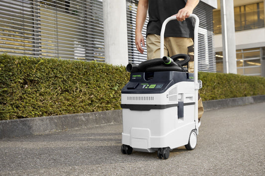 Festool CLEANTEC CT 25-Set Absaugmobil mit Saugschlauch in Anwendung auf Baustelle mit Hecken im Hintergrund