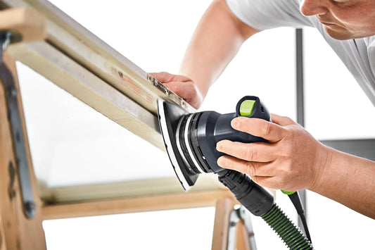 Festool DTS 400 Deltaschleifer beim Schleifen einer Holzkante, ergonomischer Handgriff mit grünem Drehschalter sichtbar.