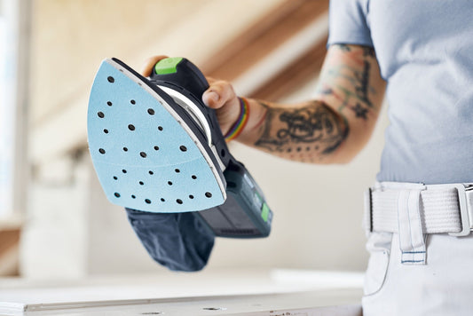 Festool Schleifschuh mit blauem StickFix Schleifbelag und Lochung in der Hand eines Handwerkers