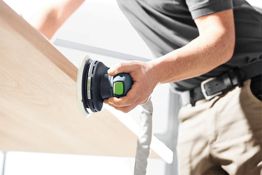 Festool ETS EC 150/3 EQ Exzenterschleifer mit grünem Schalter in Anwendung auf Holzoberfläche