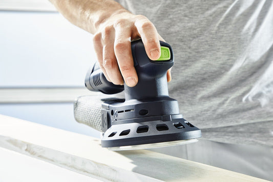 Festool Akku-Exzenterschleifer ETSC 125 wird von Hand auf Holzoberfläche angewendet, grüner Schalter sichtbar