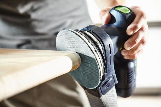 Festool Protection Pad D125 Schutzelement beim Schleifen auf Holzwerkstück, grauer Schleifteller mit grünem Button