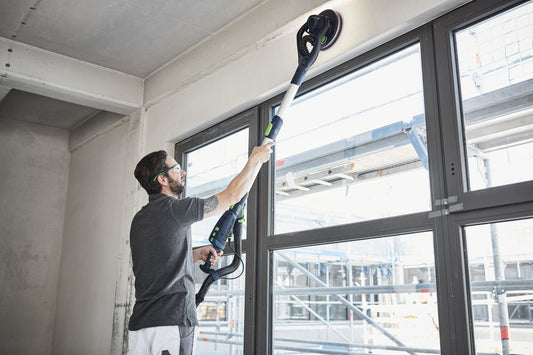 Festool PLANEX LHS 2 225 EQI Langhalsschleifer bei Deckenarbeiten mit LED-Lichtring und Absauganlage im Einsatz.