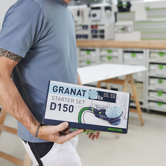 Festool Schleifscheiben Granat Set wird von einem Mitarbeiter in Werkstatt gehalten. Festool Werkstatt im Hintergrund.