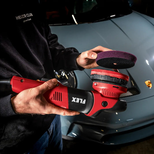 FLEX Exzenterpoliermaschine XCE 10-8 125 mit Polierpad – kraftvolle Kabelmaschine für professionelle Lackbearbeitung vor einem Porsche Sportwagen.